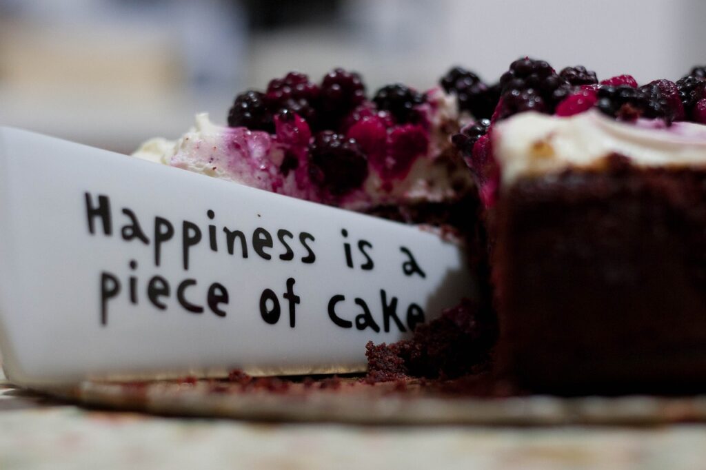 stuk tekst " happiness is a peace of cake" wat uit een stuk taart steekt