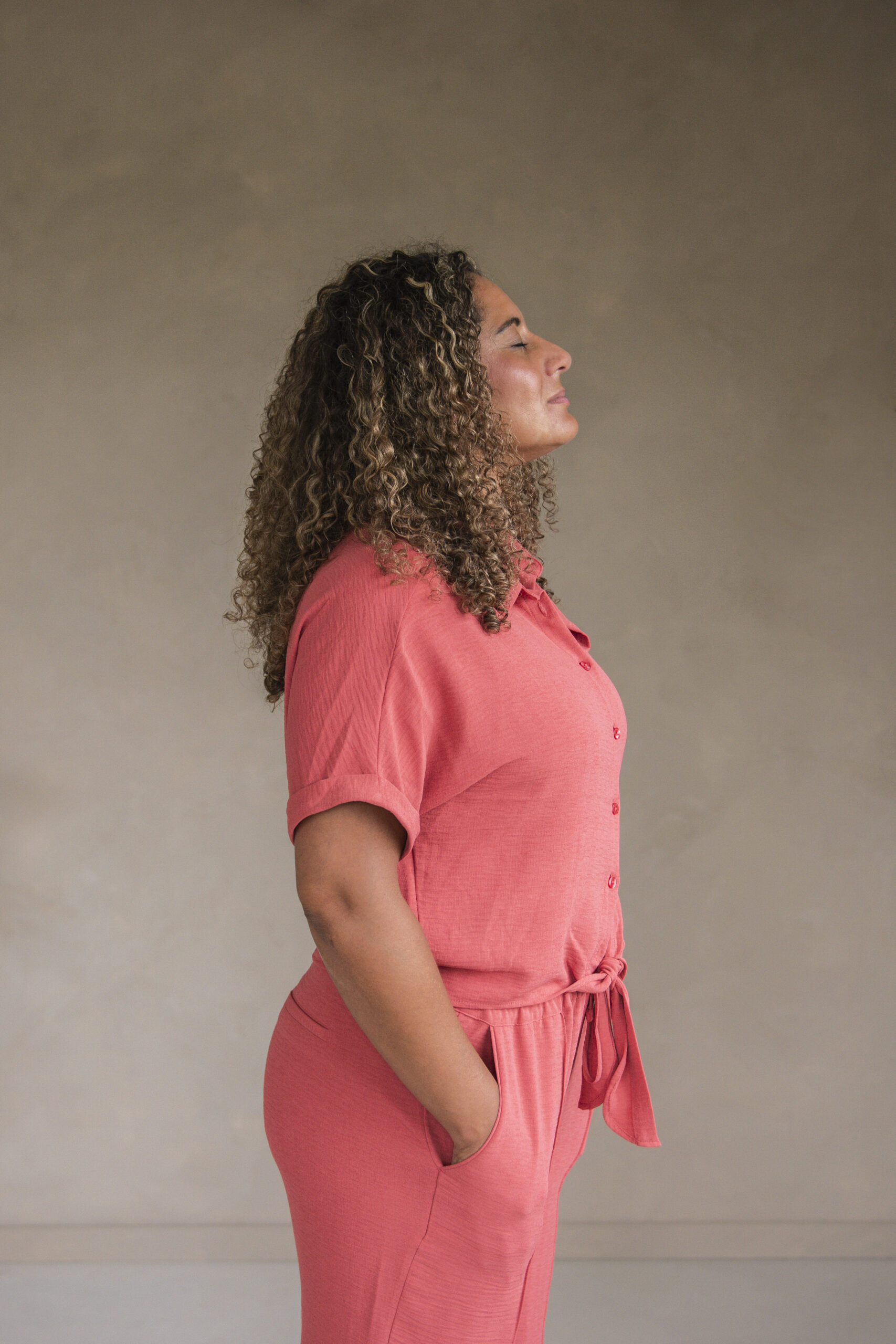vrouw met roze pak staat stevig op de grond, met haar ogen dicht